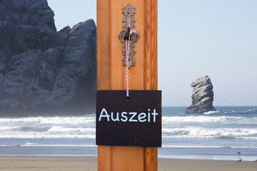 blackboard with german word for Timeout in front of beach with r