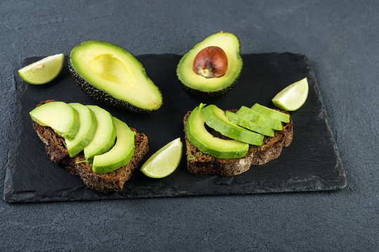 Sandwiches with  avocado and lime on dark stone board. Vegetarian  food concept.