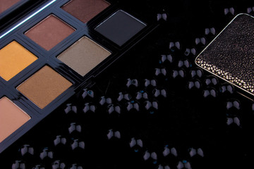 Makeup tools & Silver Accessories on Fur black background / featuring eyeshadow palette, silver rings & earrings on a fury black background