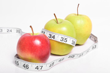 Apples with measuring tape on an isolated background. Health and sports nutrition is welcome dietitians. Apples as a diet for weight loss.