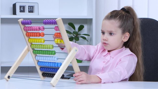 Little girl in shirt sitting at the table and said to the multicolored aba