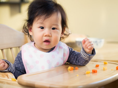 baby girl eating  vegetable first time at home
