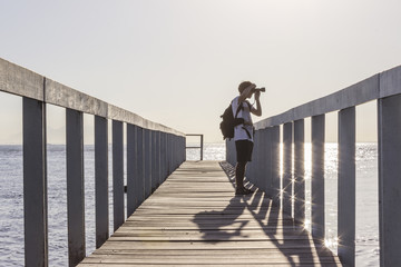 Brazil, State of Rio de Janeiro, Paqueta Island, Photographer on wooden dock during the sunset