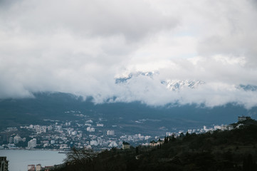 Fototapeta premium Beautiful views of the city near the sea covered with clouds from the mountains