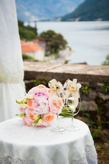 Fototapeta premium Two decorated wineglasses with champagne and wedding bouquet fro