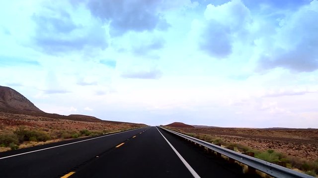 A car drives at Highway, cutting the desert of Arizona with and indescribable beauty. The road travels on painted desert, through a lava field and opens up to the State Mountain and Red Mountain.