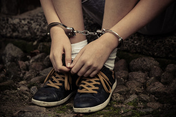 Young boy in handcuffs and sneakers