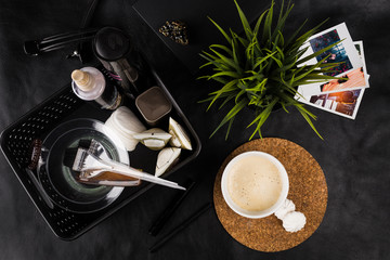 
morning cup of hot coffee on the table together with creams and oils for hair care
