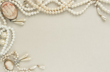 Woman's Jewellery. Frame with old vintage brooches, cameos, pearl beads, pearl earrings. Beautiful vintage jewelry on grey. Flat lay, top view