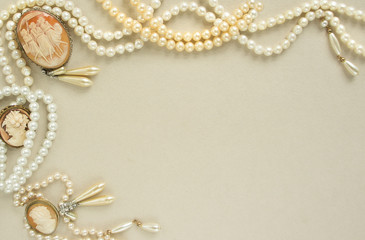 Woman's Jewellery. Frame with old vintage brooches, cameos, pearl beads, pearl earrings. Beautiful vintage jewelry on grey. Flat lay, top view