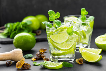 Summer mint lime refreshing cocktail mojito with rum and ice in glass on black background top view