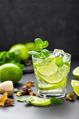 Summer mint lime refreshing cocktail mojito with rum and ice in glass on black background top view