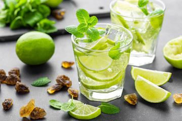 Summer mint lime refreshing cocktail mojito with rum and ice in glass on black background top view