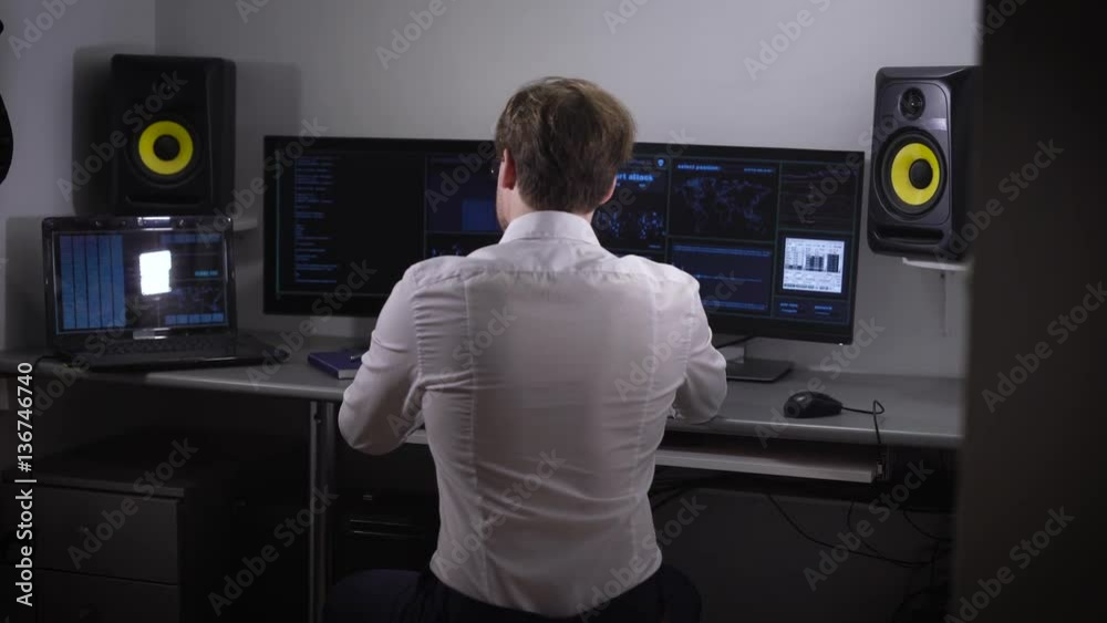 Poster young software developer analyzes and introduces a large amount of electronic data while working on 