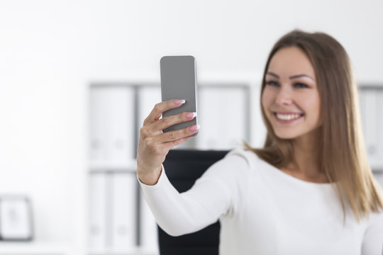 Cheerful woman in office making a selfie