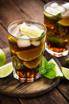 Cuba Libre cocktail with cola, lime and ice in glass, cold longdrink
