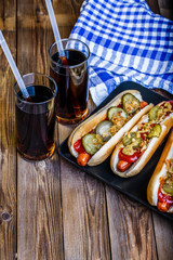 American hot dog with pickles,onions, ketchup, mustard and two soda