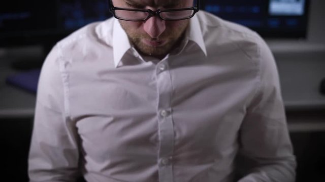 The programmer in a computer office. On a table computers. On monitors process on recovery of data is carried out. The man with the smartphone in hands sits on a chair.