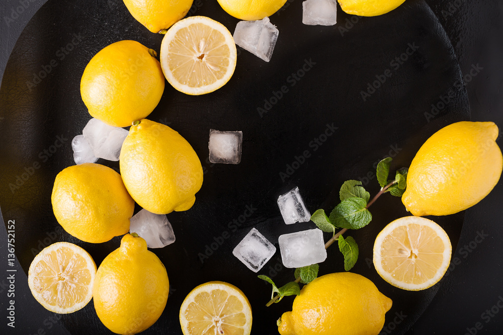 Wall mural lemons, mint, ice on a black background. healthy food concept. copyspace