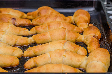 Fresh baked croissants on metallic rack and cork background