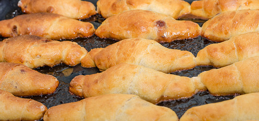 Fresh baked croissants on metallic rack and cork background