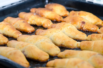 Fresh baked croissants on metallic rack and cork background