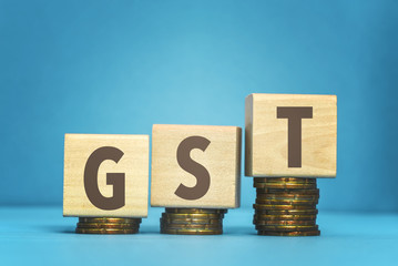 gst concept with wooden blocks and coins on table