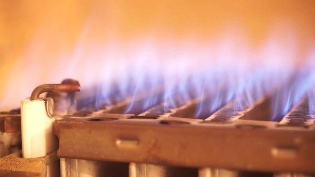 Heating at home. Blue flames of gas burner being burning, closeup detail inside of boiler furnace. 4K ProRes HQ codec