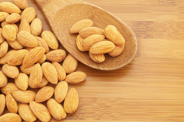 Almonds on wooden background with spoon