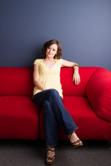Fototapeta premium Happy woman sitting in a red chair.