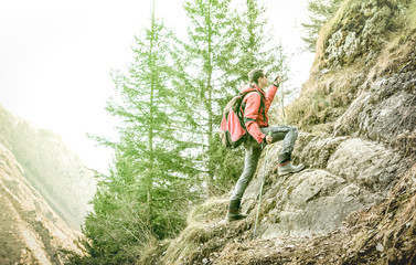 Naklejka na ściany i meble Adventurous explorer trekking and climbing on french alps - Hiker with backpack and sticks walking on mountain - Hiking travel concept with sporty guy at excursion in wild nature - Greenery filter