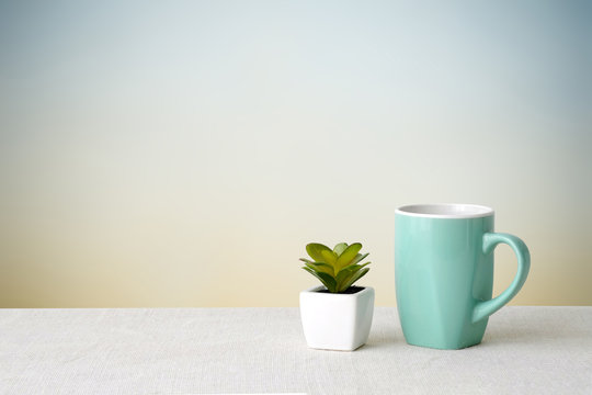 Green coffee cup on sack tablecloth over green cement wall backg