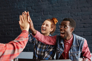 Teamwork, cooperation, partnership and success. Interracial group of happy creative people raising hands and giving high five to each other, cheering and celebrating start of their common project