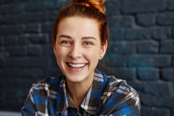 Close up portrait of beautiful young woman with ginger hair and clean healthy skin looking at camera with cheerful expression, happy with some positive news. Human face expressions and emotions