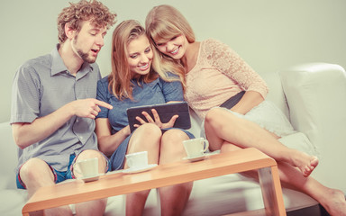 Friends relaxing browsing internet on tablet.