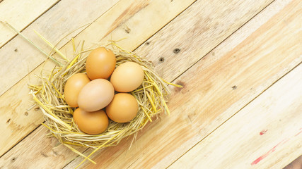 Eggs in the straw on a wooden table.