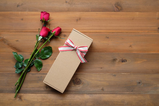 Red roses and vintage gift box on vintage wood background