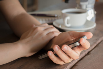 Hand on smartphone at wooden table