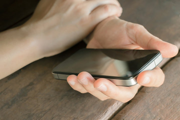 Hand on smartphone at wooden table