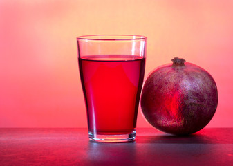 A glass of pomegranate juice with pomegranate fruits on wooden table. Vitamins. Healthy drink concept.