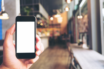 Mockup image of hand holding black mobile phone with blank white screen in modern cafe
