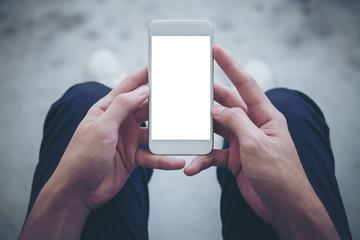 Mockup image of a man sitting on the street and holding white mobile phone with blank white screen   