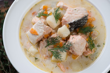 Close-up of fish soup with salmon in a white glass plate