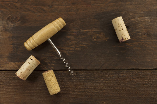Photo of wine corkscrew and corks on dark background