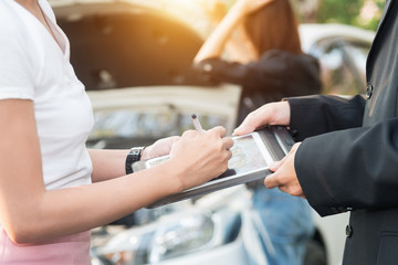 Asian women and insurance agent examining car after accident