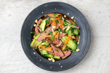 Flat top view of a plate of asian beef salad. Inspired by Thai & Vietnamese cuisine, this salad is made with fresh healthy vegetables (carrots, onions, cucumber, etc) and a nicely seared flank steak