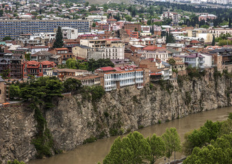 Fototapeta na wymiar Georgia, Tbilisi. View from the fortress Narikala on Avlabari./Georgia, Tbilisi. View from the fortress Narikala on Avlabari district , houses on a cliff , leaving the water in the Kura River .