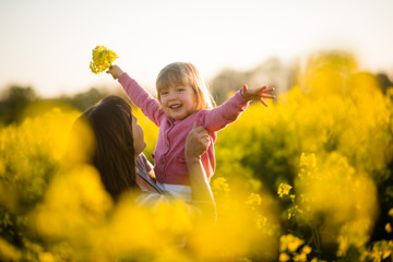Carefree baby and mother on nature in rapeseed field