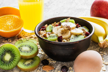 oatmeal porridge in a bowl with fruits, nuts, egg and fresh orange juice