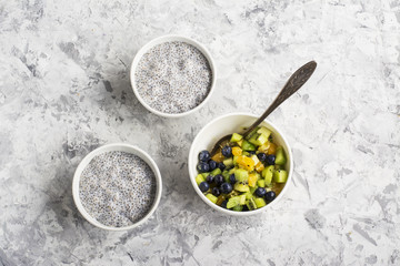 Chia Pudding for breakfast or snack with fruit salad on the side dish of blueberries, kiwi and orange with honey, almonds and pumpkin seeds. An example of a seasonal menu. Top view.